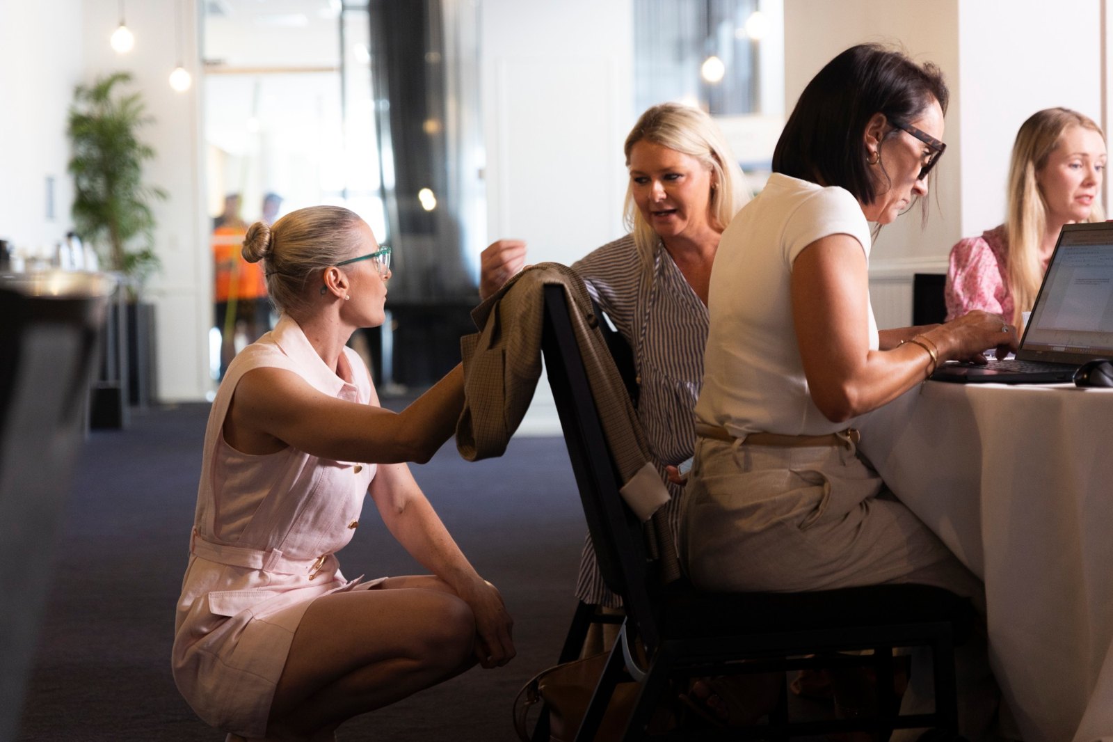 Tash Miller crouching beside a table, helping workshop attendees one-on-one